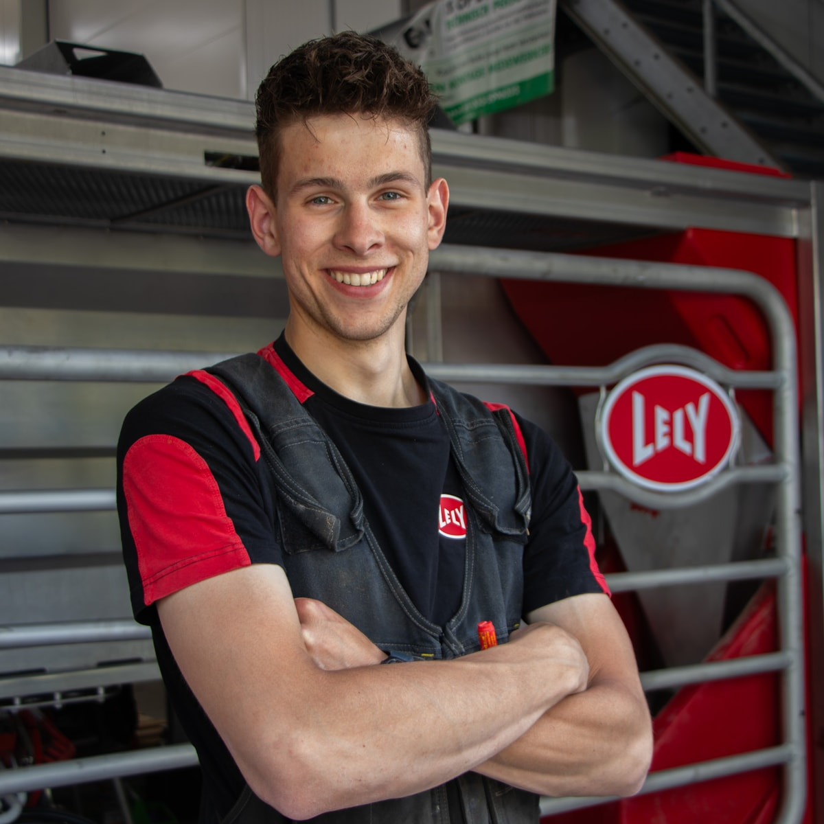 Jonge Lely-collega lacht in werkkleding voor een Lely-machine