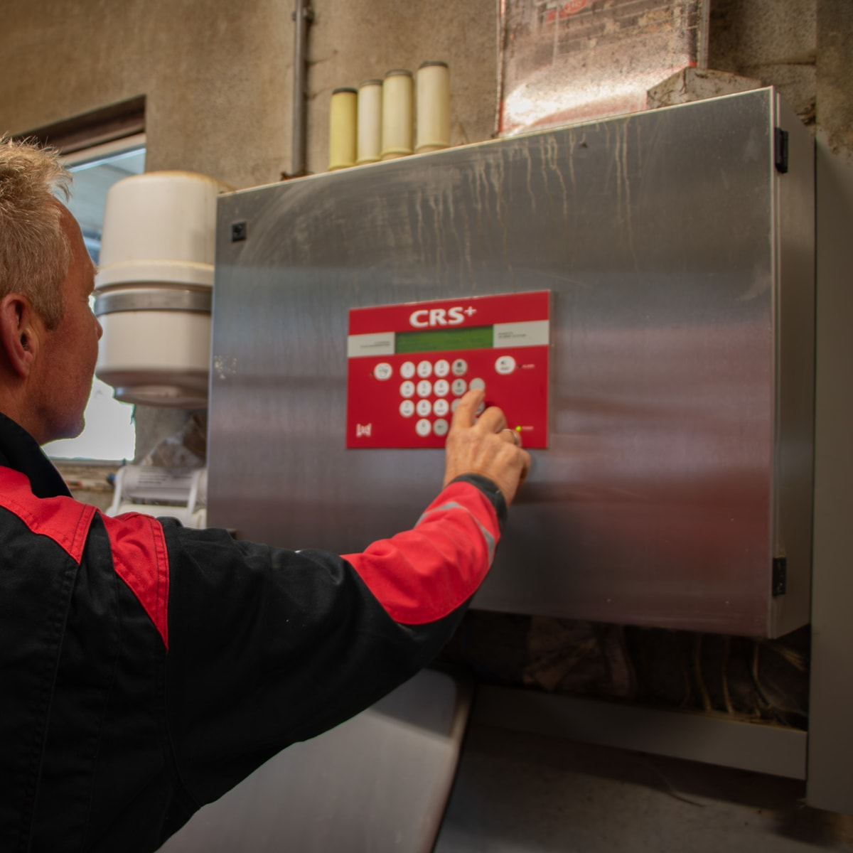 Monteur bedient het CRS+ bedieningspaneel van een melkrobot